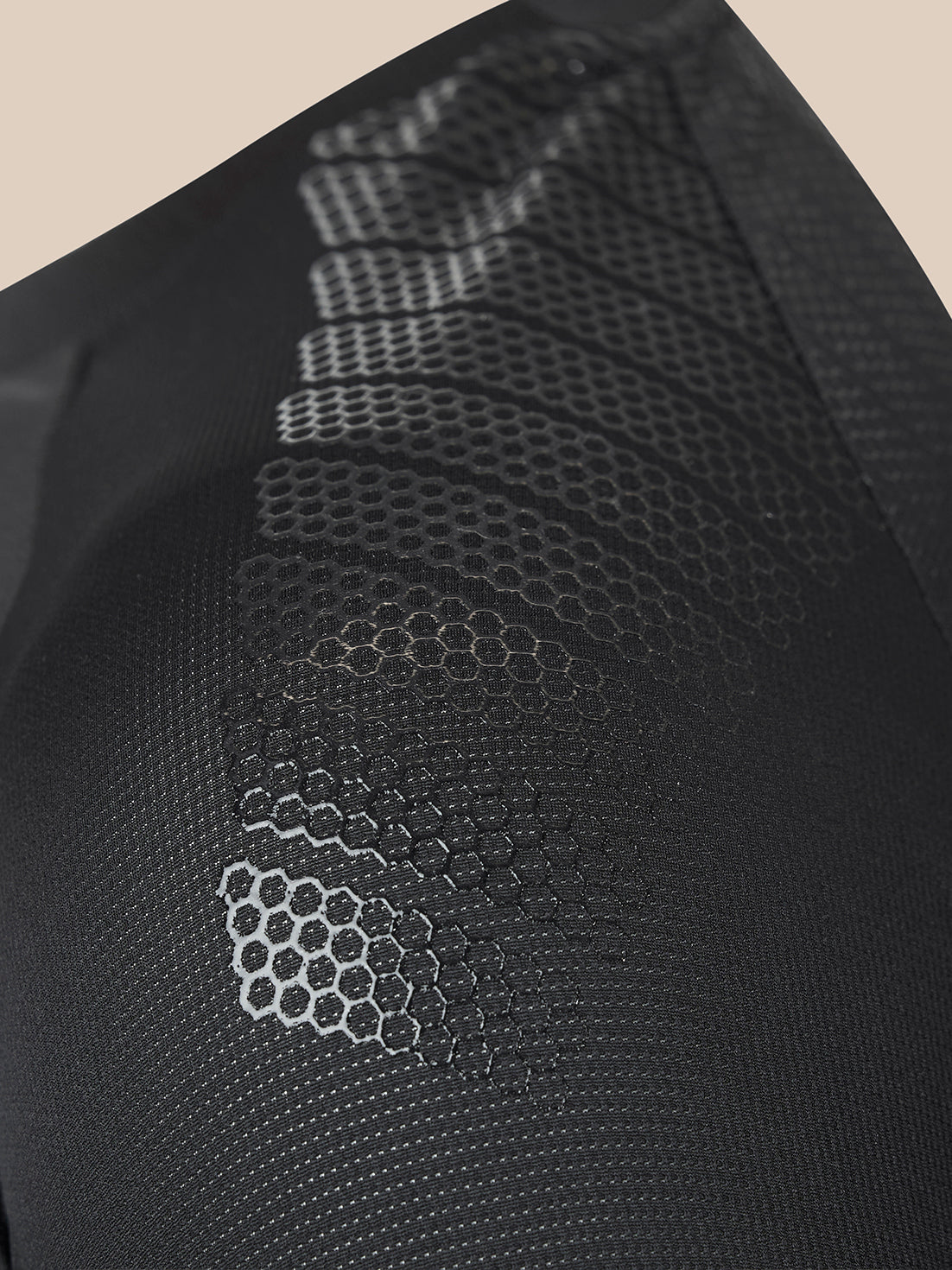 Close-up of a black textured mesh garment featuring a raised honeycomb pattern and a subtle diagonal stitched design.