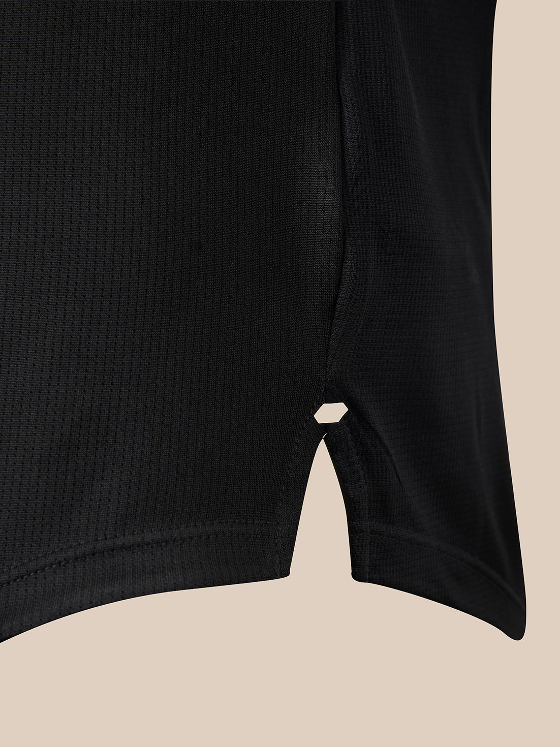 Close-up of a black ribbed athletic top showing a split V-neckline with a small geometric cutout, set against a solid beige background.