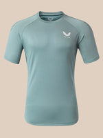 A light blue athletic short-sleeve t-shirt with a white wing logo and the brand name 'Castore' printed on the left chest, displayed on a neutral beige background.