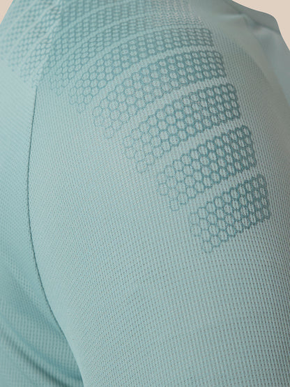 Close-up of a light blue athletic mesh garment with tonal geometric honeycomb patterns on the shoulder and upper arm.