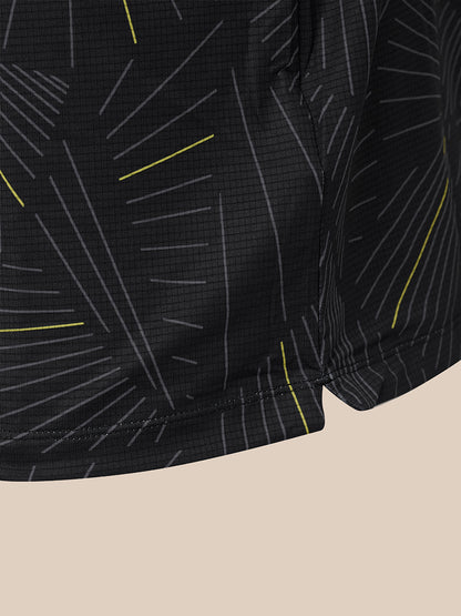 Close-up of black athletic shorts with a geometric line pattern in gray and bright yellow, shown against a solid beige background.