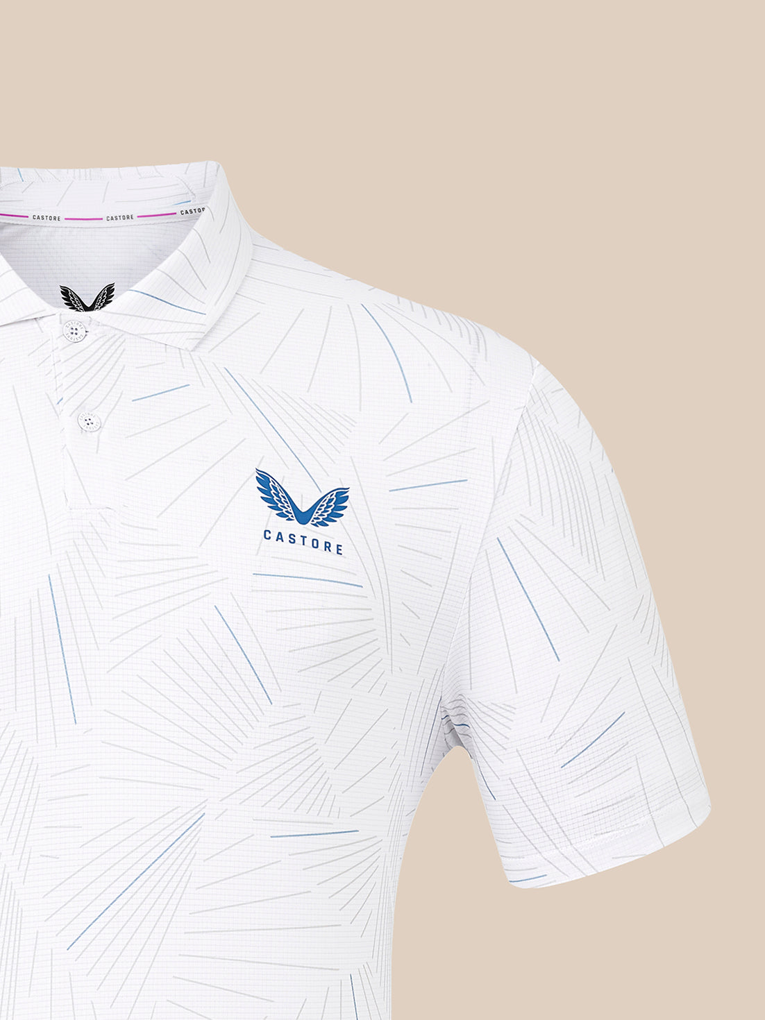 White short-sleeve polo shirt with a subtle geometric line pattern, featuring a blue winged Castore logo on the left chest and a matching black logo on the inside neck label, set against a solid beige background.