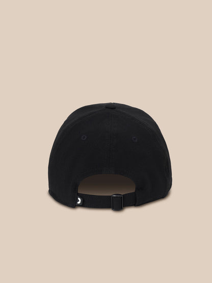 A black baseball cap shown from the back, featuring an adjustable strap with a small white logo, set against a solid beige background.