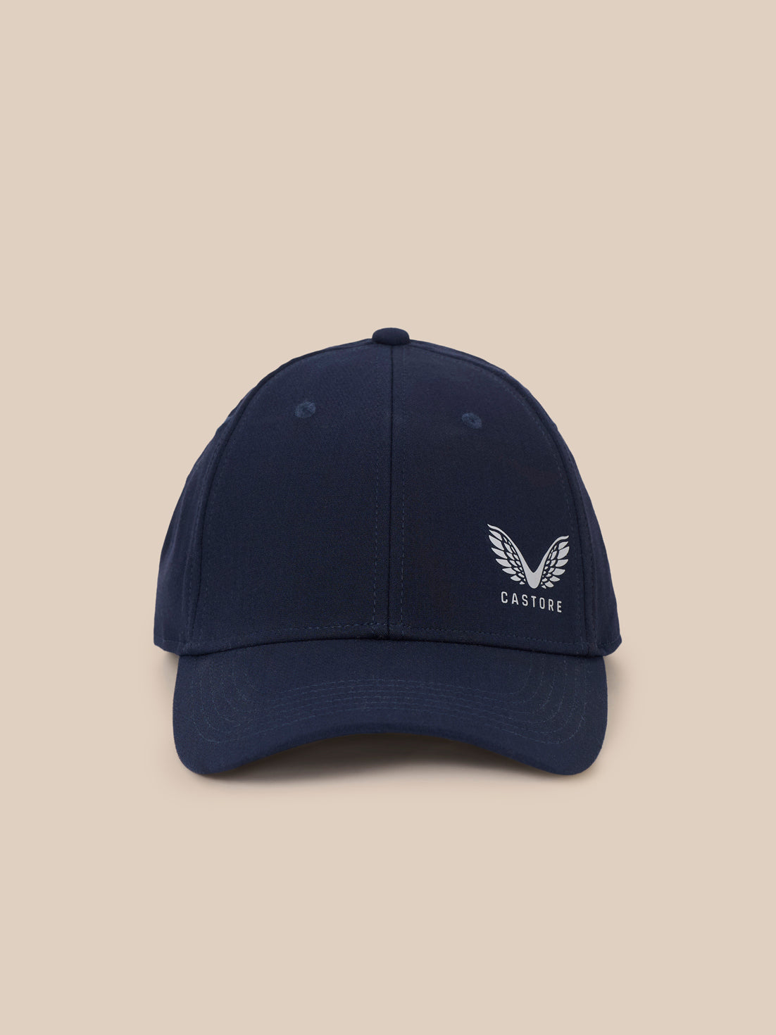 A navy blue baseball cap with a white embroidered winged logo and the word 'CASTORE' on the front, set against a solid beige background.