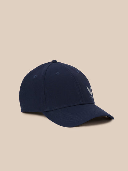 A navy blue baseball cap with a small white embroidered winged logo on the side, displayed against a solid beige background.