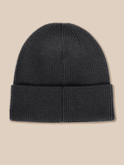 A dark charcoal gray ribbed knit beanie hat with a folded cuff, shown flat against a solid beige background.