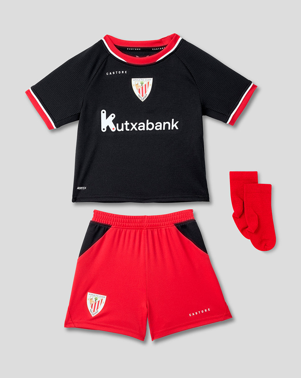 Infant away kit laid out featuring a black jersey with red trim, red shorts and red socks