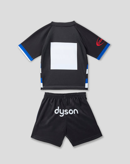 A two-piece kids' athletic set consisting of a black short-sleeve jersey with blue and white sleeve and side accents, and matching black shorts with 'dyson' printed in white on the front, shown on a light gray background.