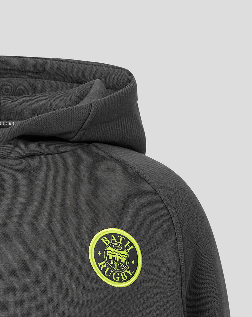 Close-up of a dark gray hooded sweatshirt showing the shoulder and chest area with a circular yellow and green 'Bath Rugby' crest patch on the left chest, set against a light gray background.