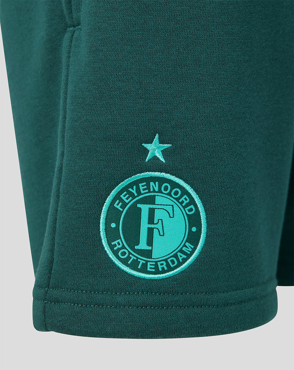 Close-up of teal green shorts featuring the Feyenoord Rotterdam crest embroidered near the hem with a star above.