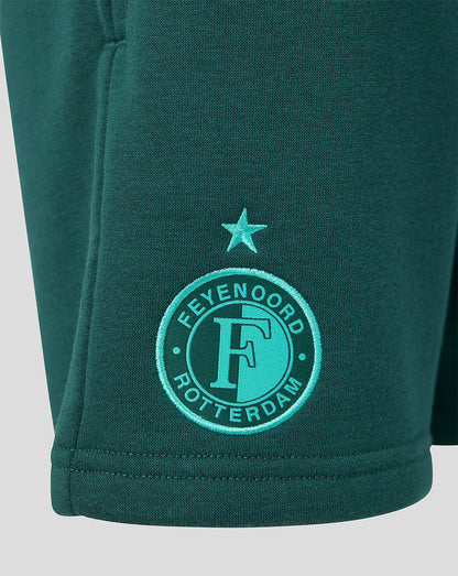 Close-up of teal green shorts featuring the Feyenoord Rotterdam crest embroidered near the hem with a star above.