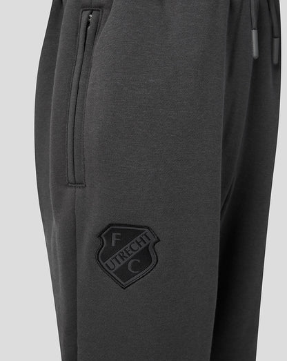 Close-up of dark grey FC Utrecht travel fleece pants showing a zippered side pocket and the FC Utrecht crest on the leg
