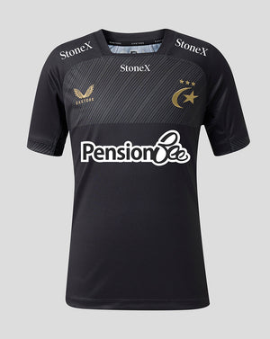 A black short-sleeve sports jersey with a textured dark gray chest panel, featuring the 'Pension Bee' sponsor logo in white across the center, 'StoneX' branding on the shoulders, and a gold winged bird crest with 'Castore' on the right chest, alongside a gold crescent and stars emblem on the left chest, set against a solid light gray background.