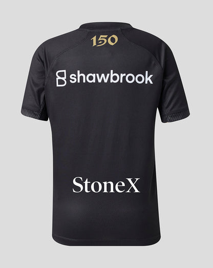 Black short-sleeve athletic jersey shown from the back, featuring a gold '150' print at the collar, a large white 'shawbrook' sponsor logo across the upper back, and a white 'StoneX' sponsor logo near the lower back, set against a solid light gray background.