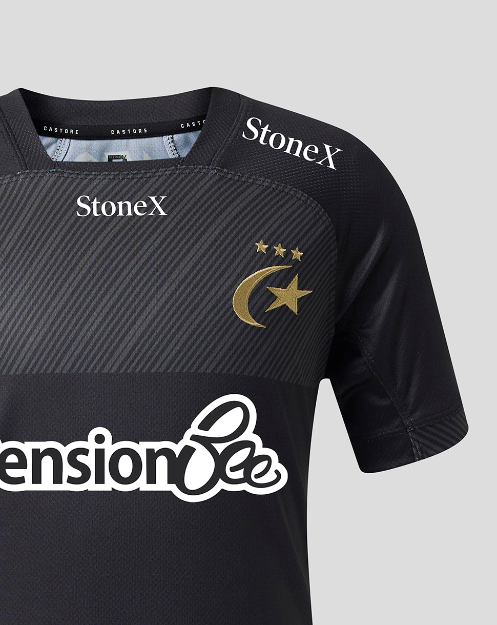 Close-up of a black short-sleeve sports jersey with diagonal textured panels, featuring the gold crescent and star emblem with three stars on the chest, StoneX logos on the shoulders, and a large white 'Pension Bee' sponsor logo across the front.