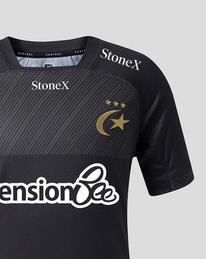 Close-up of a black short-sleeve sports jersey with diagonal textured panels, featuring the gold crescent and star emblem with three stars on the chest, StoneX logos on the shoulders, and a large white 'Pension Bee' sponsor logo across the front.