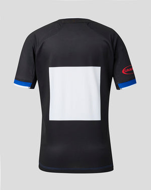 Black short-sleeve athletic jersey shown from the back, featuring a large blank white square on the back, blue trim on the sleeve cuffs, and a red and blue 'GRAM' logo on the right sleeve, set against a solid gray background.