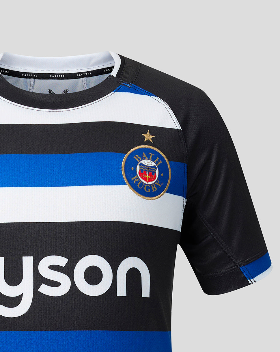 A close-up of a Bath Rugby sports jersey with black, white, and blue horizontal stripes, featuring the Bath Rugby club crest on the chest and a partial white dyson sponsor logo on the front.