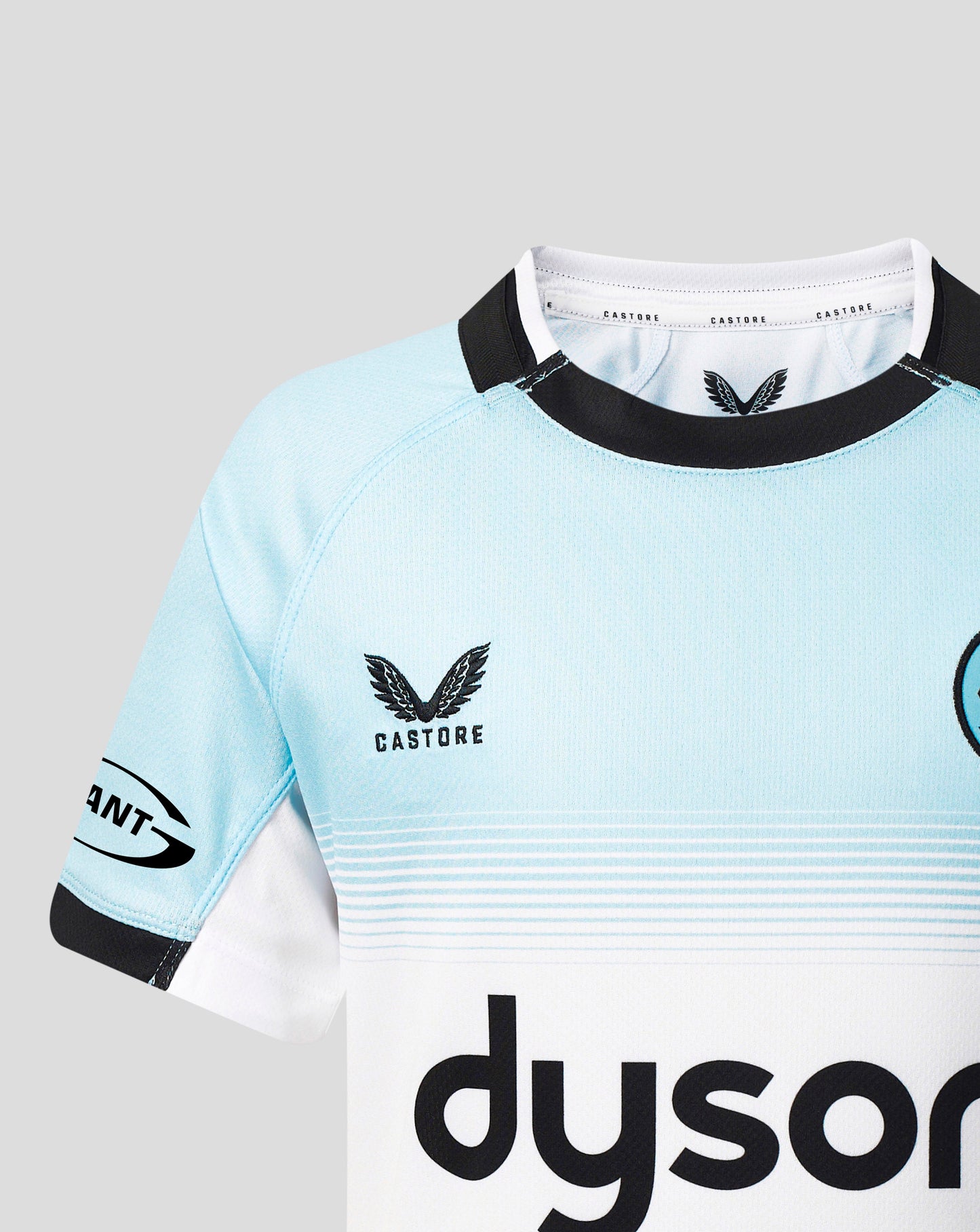 A close-up of a Castore rugby jersey in light blue and white with black trim, featuring the Castore wing logo and a partial Dyson sponsor logo.