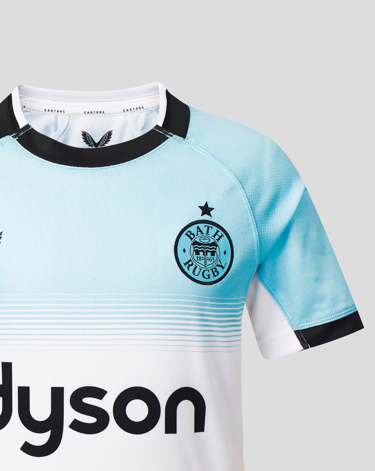 A close-up of a Bath Rugby rugby jersey in light blue and white with black trim, featuring the Bath Rugby crest on the chest and a visible Dyson sponsor logo.