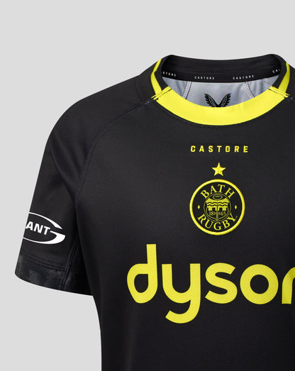 A close-up of a Bath Rugby football jersey in black with bright yellow accents, featuring the club's crest and a visible Dyson sponsor logo on the front.