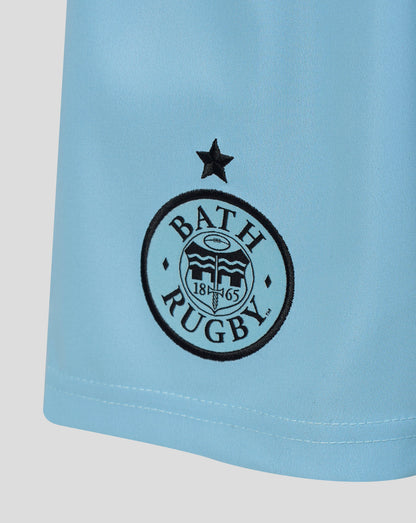 Close-up of a light blue athletic jersey or shorts leg with a black circular Bath Rugby logo and star emblem printed on the front.