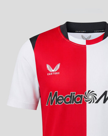 Close up of Feyenoord Junior home shirt chest with red and white split crest badge and Media Markt sponsor across front