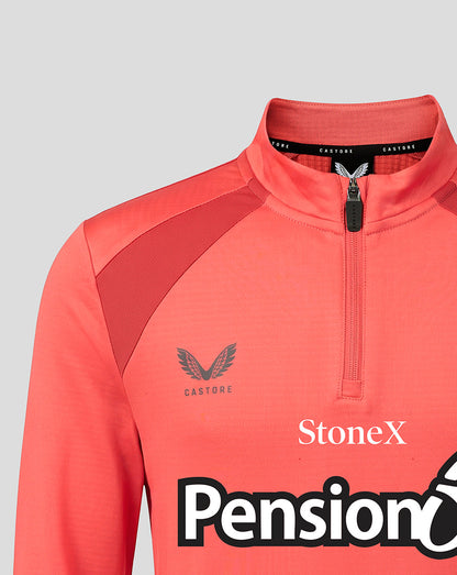 Close-up of a coral pink athletic quarter-zip pullover with a mock neck collar, featuring the Castore wing logo on the chest, a black zipper, and sponsor logos StoneX and Pension X.