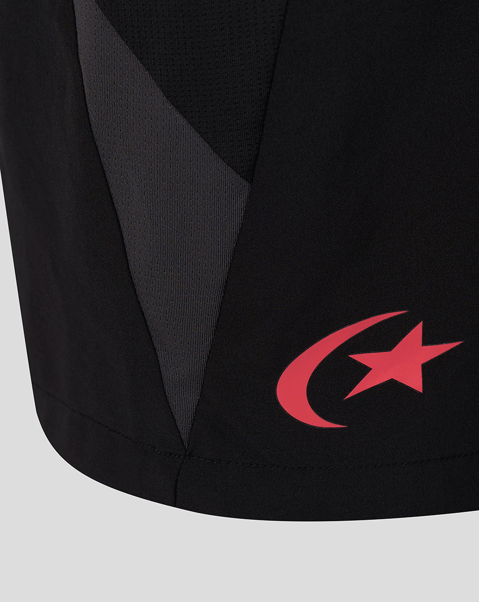 Close-up of a black athletic garment with a red crescent and star logo on the lower side, showing a textured panel and a dark gray side stripe.