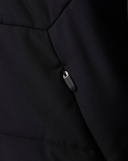 Close-up of a black quilted jacket showing a side pocket with a black zipper pull and fine fabric texture.