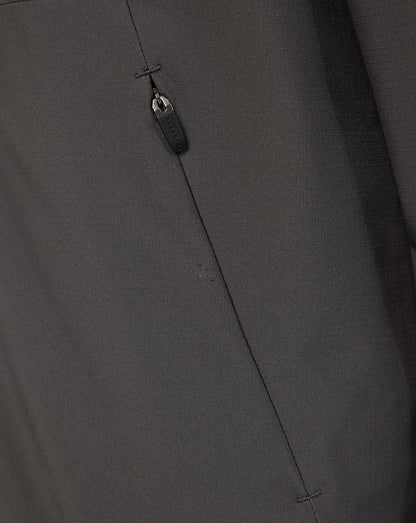 Close-up of a dark gray fabric garment showing a vertical seam, a small stitched detail, and a dark zipper pull.