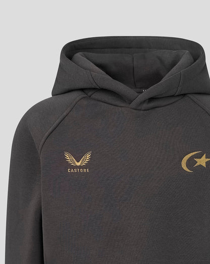 A close-up of a dark gray hooded sweatshirt featuring a gold Castore wing logo with 'CASTORE' text on the left chest and a gold crescent and star logo on the right chest, set against a light gray background.