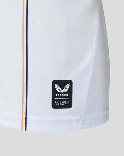 Close up of white jersey hem showing Castore authentic product badge and navy orange piping