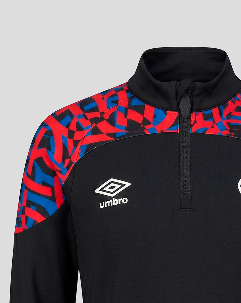 A close-up of a black athletic quarter-zip pullover with a red and blue geometric pattern on the shoulders and upper sleeves, featuring a white Umbro logo on the chest.