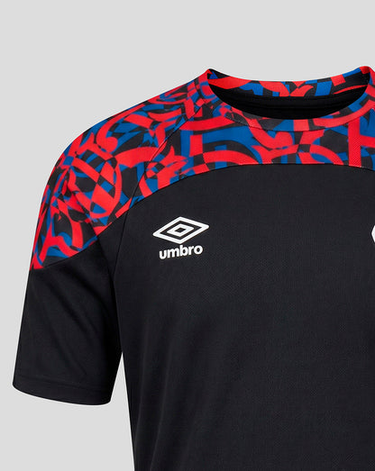 A close-up of an Umbro soccer jersey with a black body, red and blue abstract patterned shoulder yoke, and a white Umbro logo on the chest.