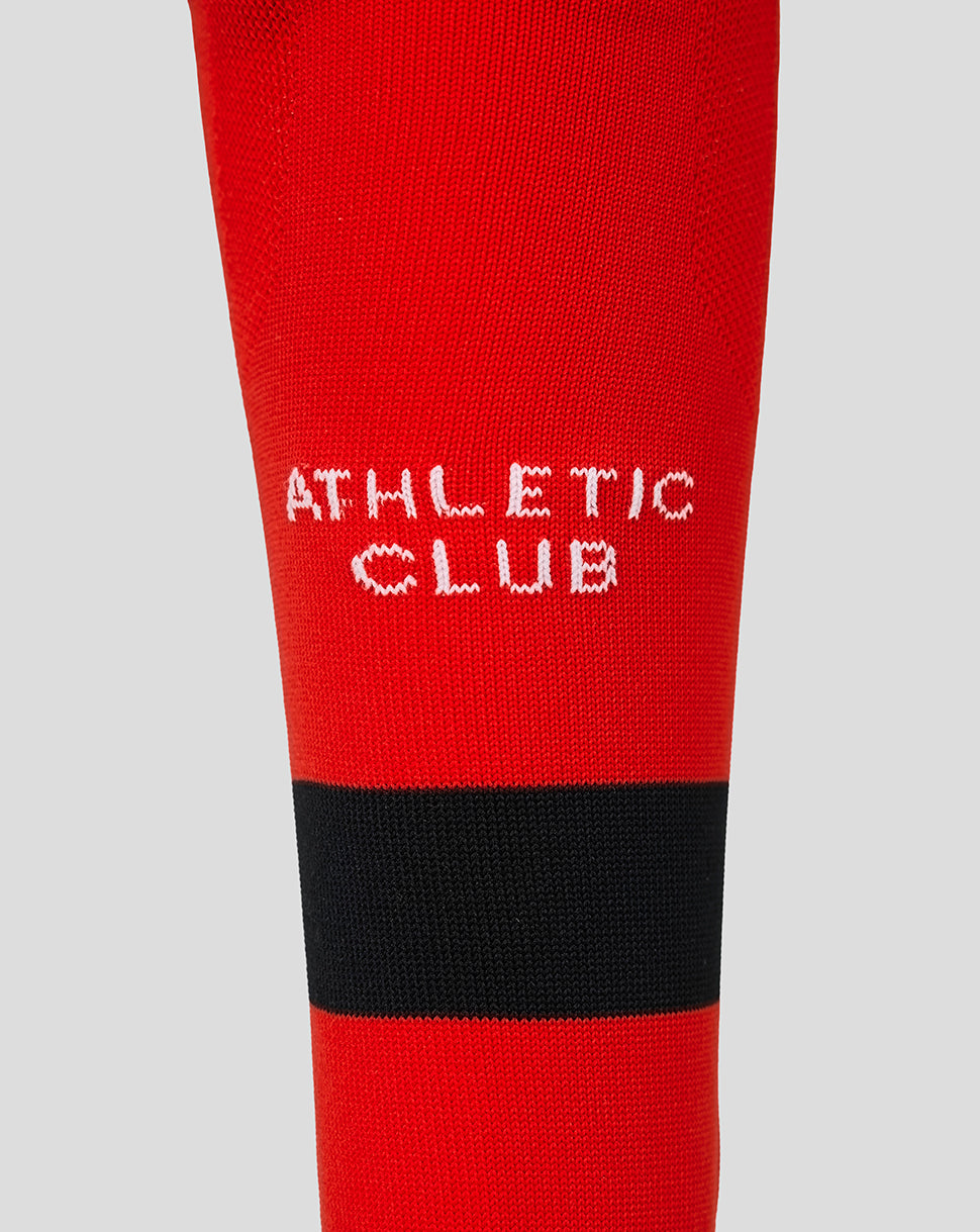 Close up of red Athletic Club junior away sock with a black band and white lettering.