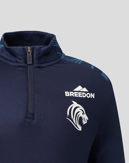 Close-up of a navy blue quarter-zip pullover jacket featuring a white 'BREEDON' text logo and a white lion head graphic on the chest, set against a light gray background.