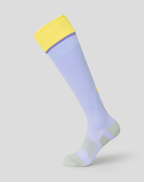 A single knee-high athletic sock shown on a light gray background. The sock features a light lavender body, a bright yellow cuff, a thin purple stripe near the top, and a light gray heel and toe.