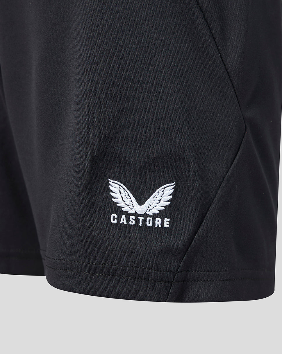 Close up of white winged Castore logo embroidered on the hem of black shorts