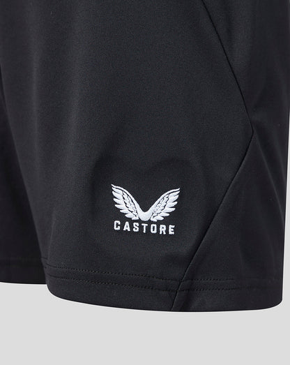 Close up of white winged Castore logo embroidered on the hem of black shorts