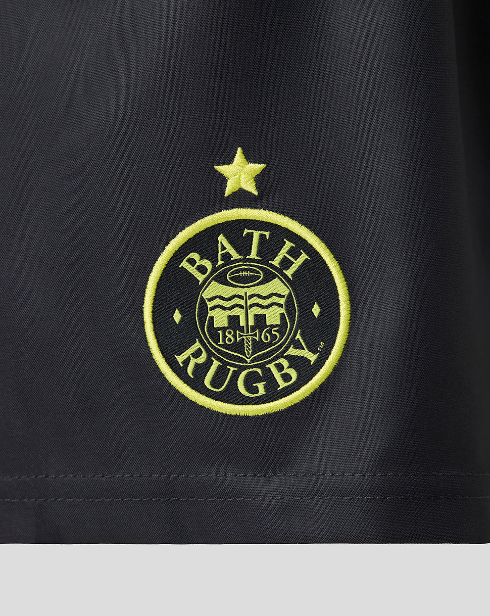 Close-up of a black athletic fabric with an embroidered circular Bath Rugby logo in bright yellow-green thread, featuring a star above and the text 'BATH RUGBY' with '1865' in the center.