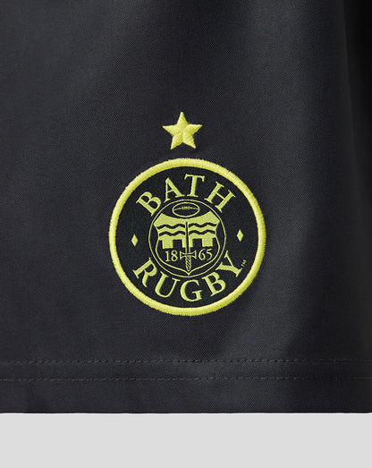 Close-up of a black athletic fabric with an embroidered circular Bath Rugby logo in bright yellow-green thread, featuring a star above and the text 'BATH RUGBY' with '1865' in the center.