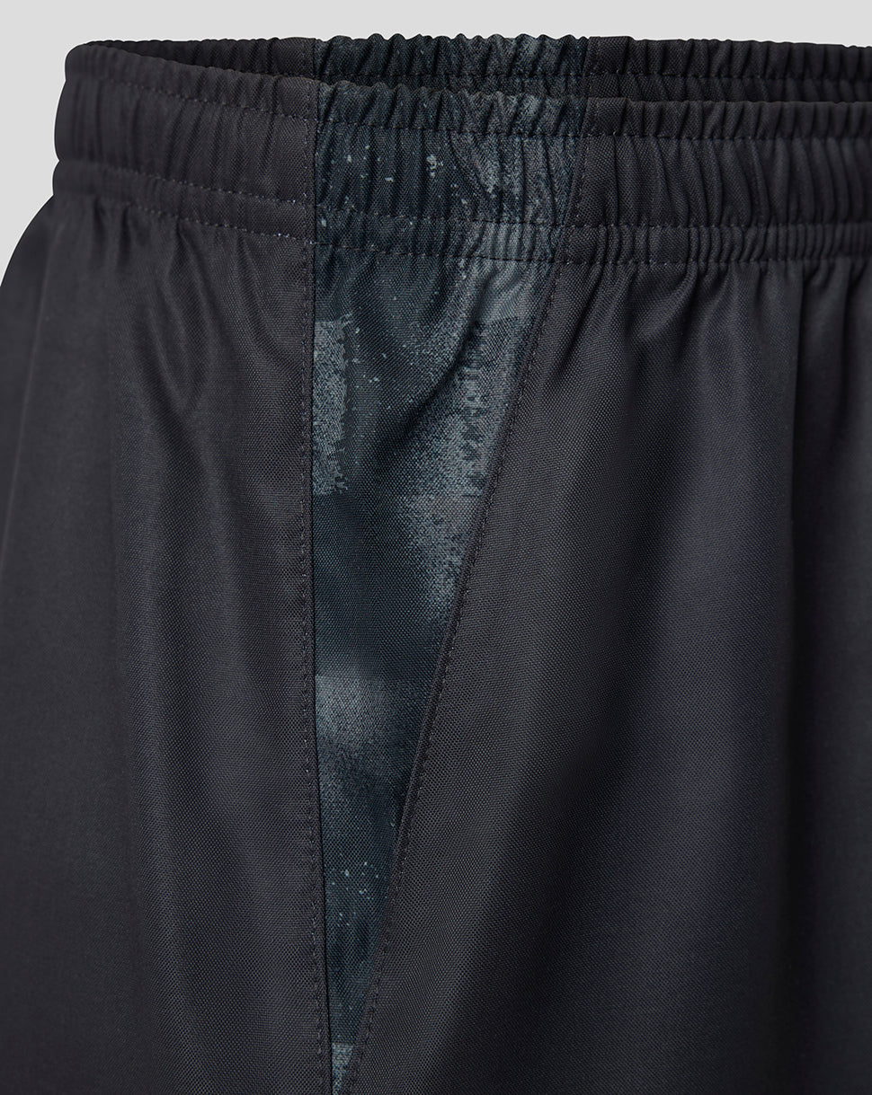 Close-up of black athletic shorts showing the elastic waistband, side seam, and a subtle tonal patterned lining.