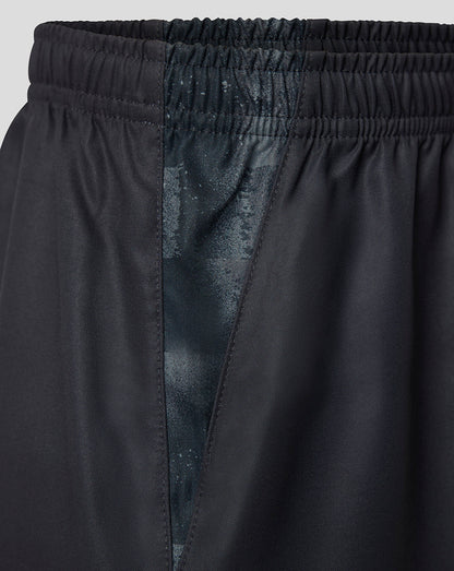 Close-up of black athletic shorts showing the elastic waistband, side seam, and a subtle tonal patterned lining.