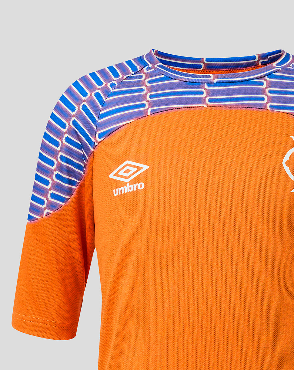 Close-up of an orange football jersey with a blue and purple geometric patterned yoke and white Umbro logo on the chest.