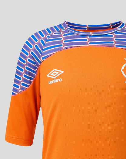 Close-up of an orange football jersey with a blue and purple geometric patterned yoke and white Umbro logo on the chest.