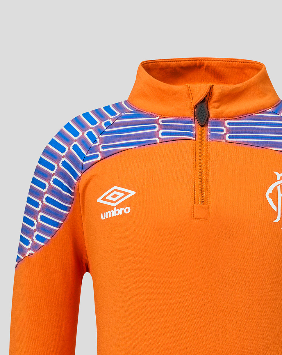 Close-up of an orange football jersey with a blue and purple patterned shoulder yoke, featuring the white Umbro logo on the chest.