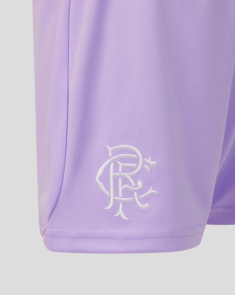 Close-up of a lavender athletic shorts leg featuring an embroidered white monogram logo near the hem, set against a solid light gray background.