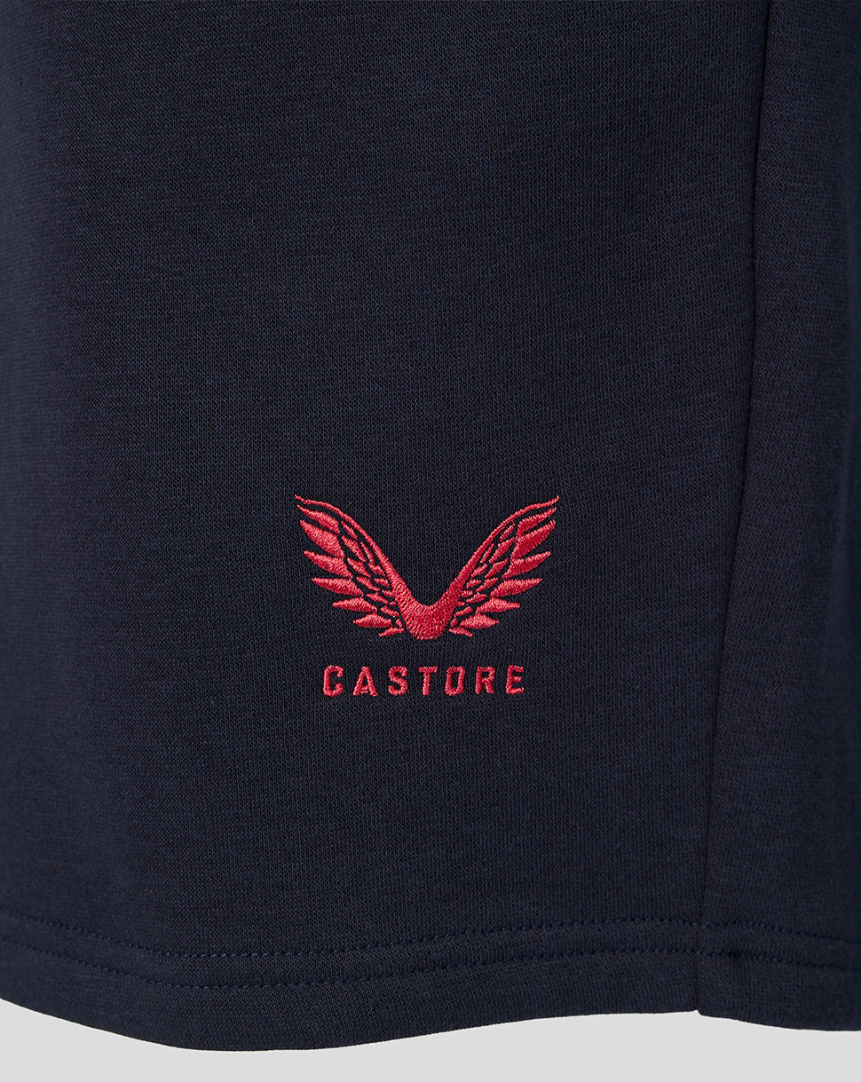Close-up of red Castore logo embroidered on navy FC Twente travel fleece shorts fabric.