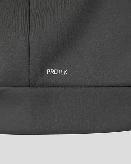 Close-up of a dark gray athletic jacket showing the 'PROTEK' logo embroidered on the chest, with a light gray background visible at the bottom.